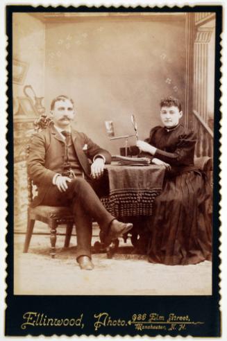A Seated Couple with a Device for Viewing Photographs